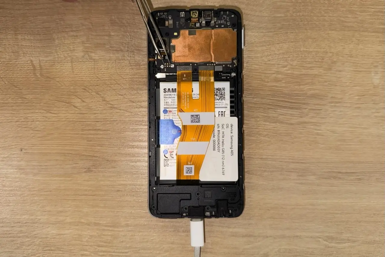 The view of a Samsung Galaxy A05 smartphone with the back cover removed and test points shorted